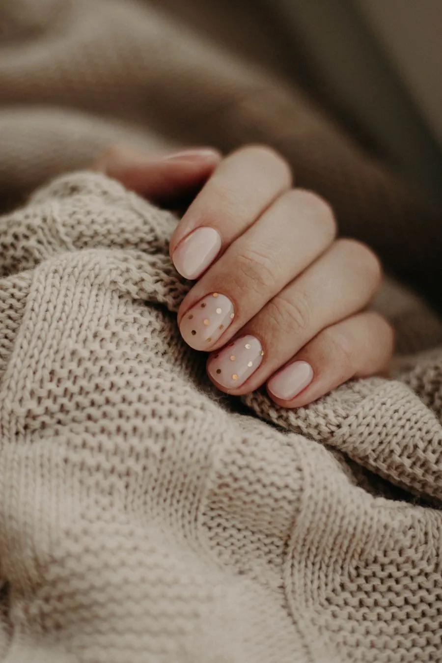 Milky mocha nude nails resting on a knit sweater